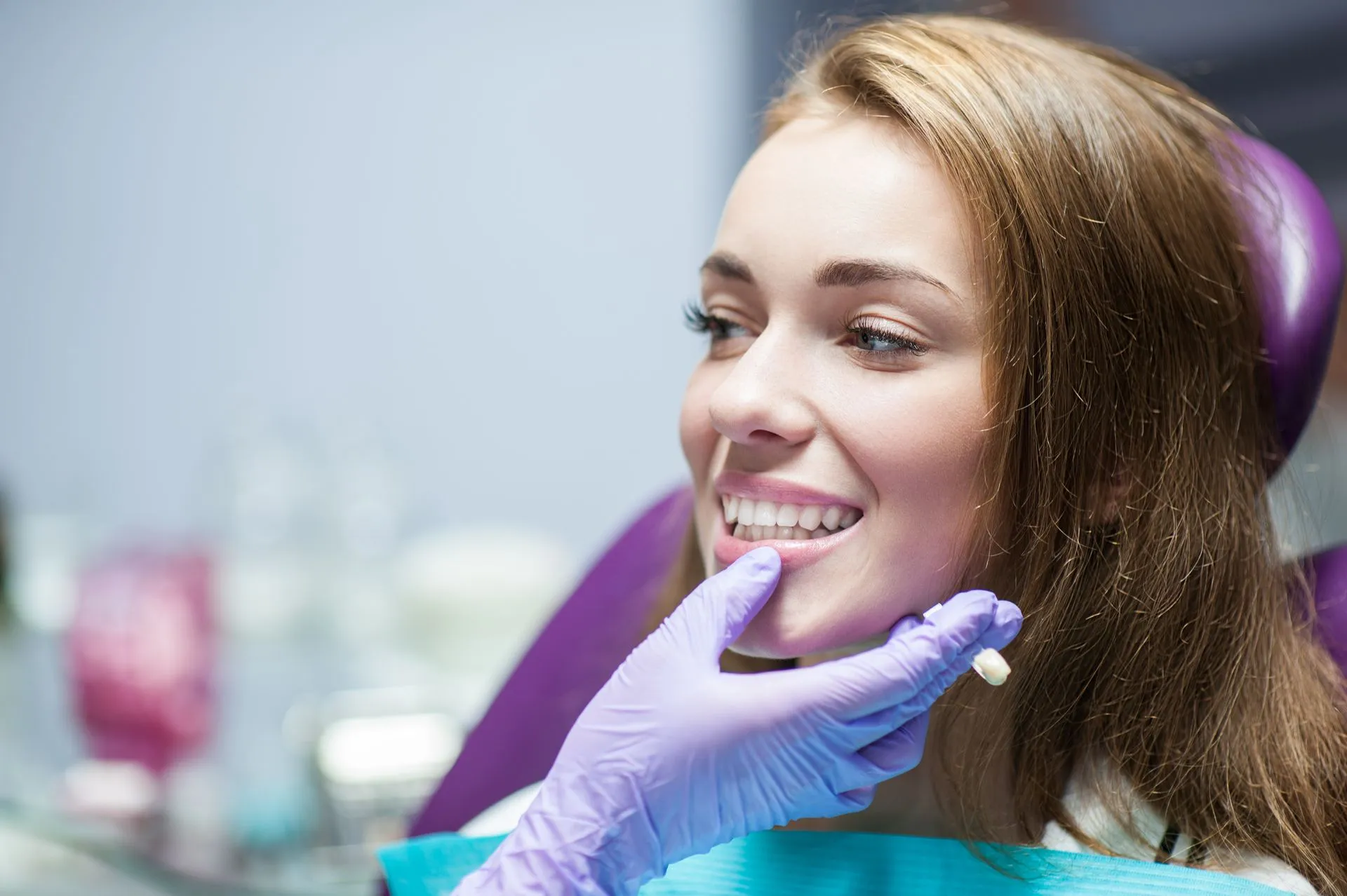 Dental professional examining a patient’s front teeth during a crown fitting appointment.