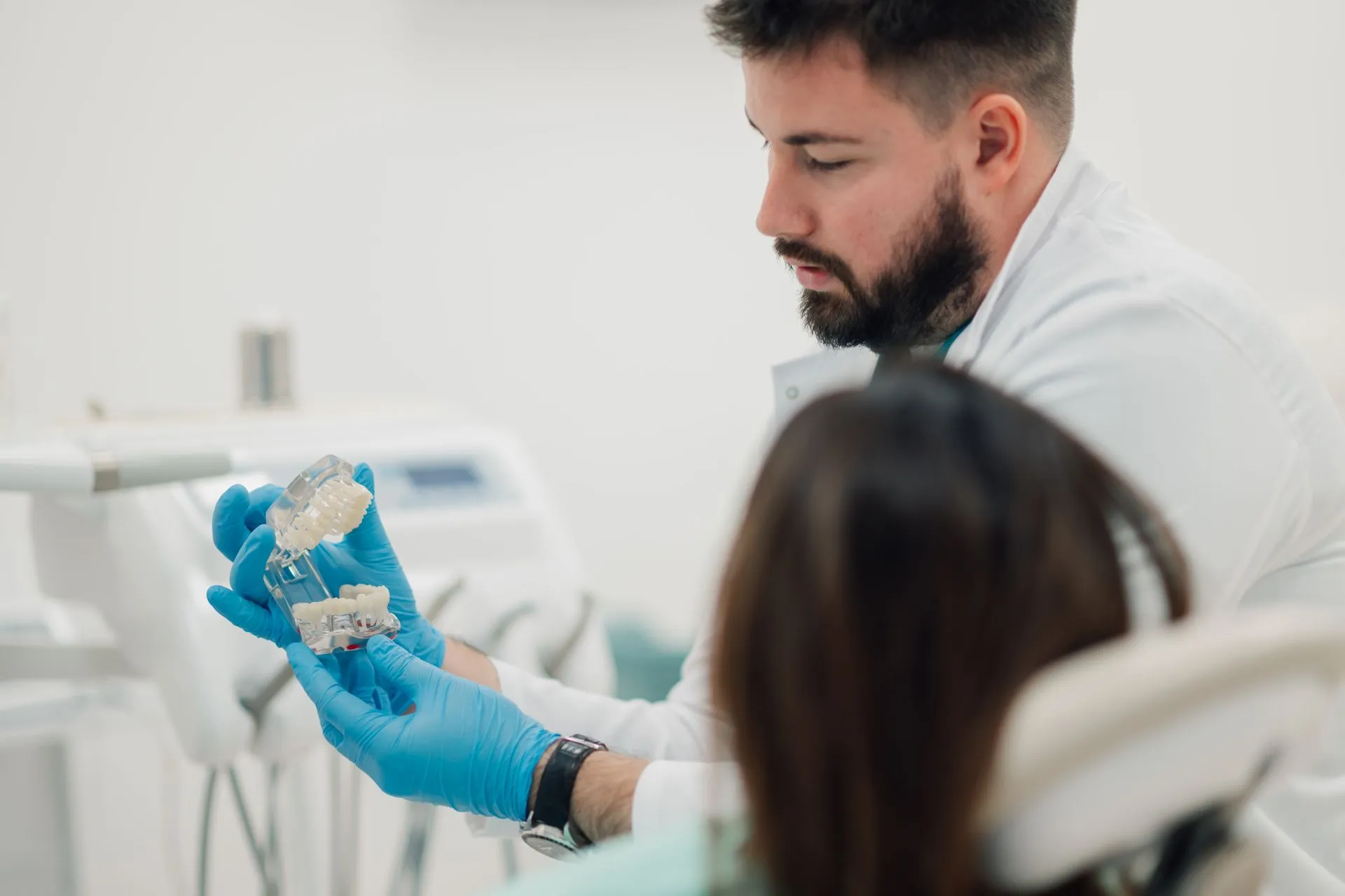 A dentist is showing a denture model to a patient while explaining denture services.