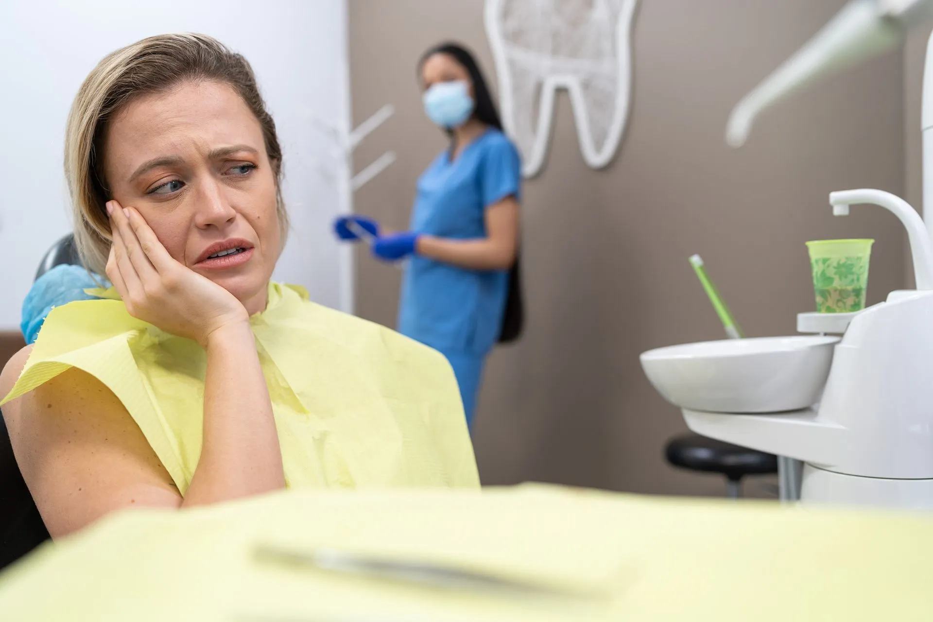 A woman in a dental chair with tooth pain receiving urgent dental emergency services at the clinic.